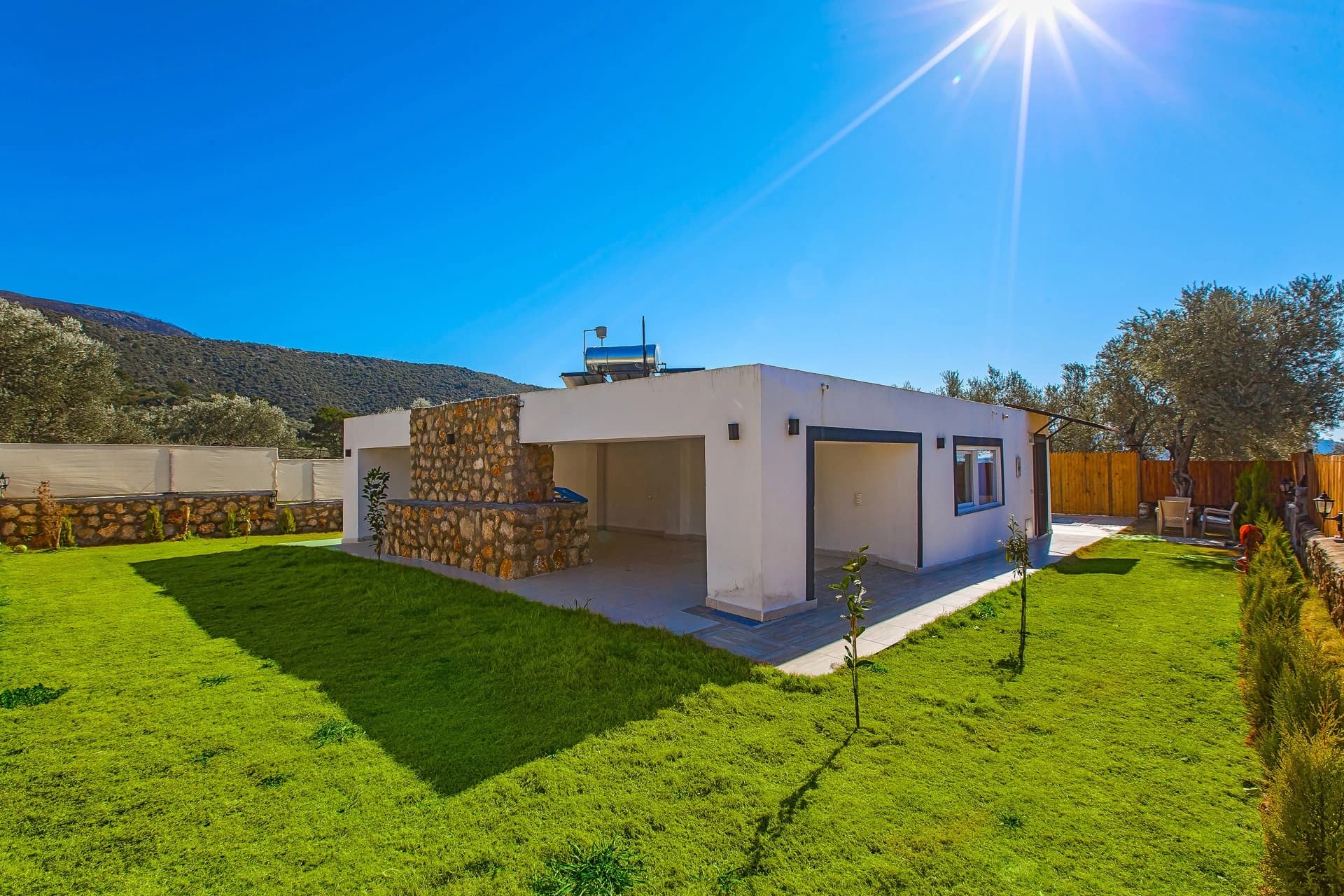 Abgeschiedene Waldvilla mit privatem Pool und Jacuzzi-Suite bei Kalkan – Villa front elevation showcasing clean modern design with stone features and scenic mountain surroundings.