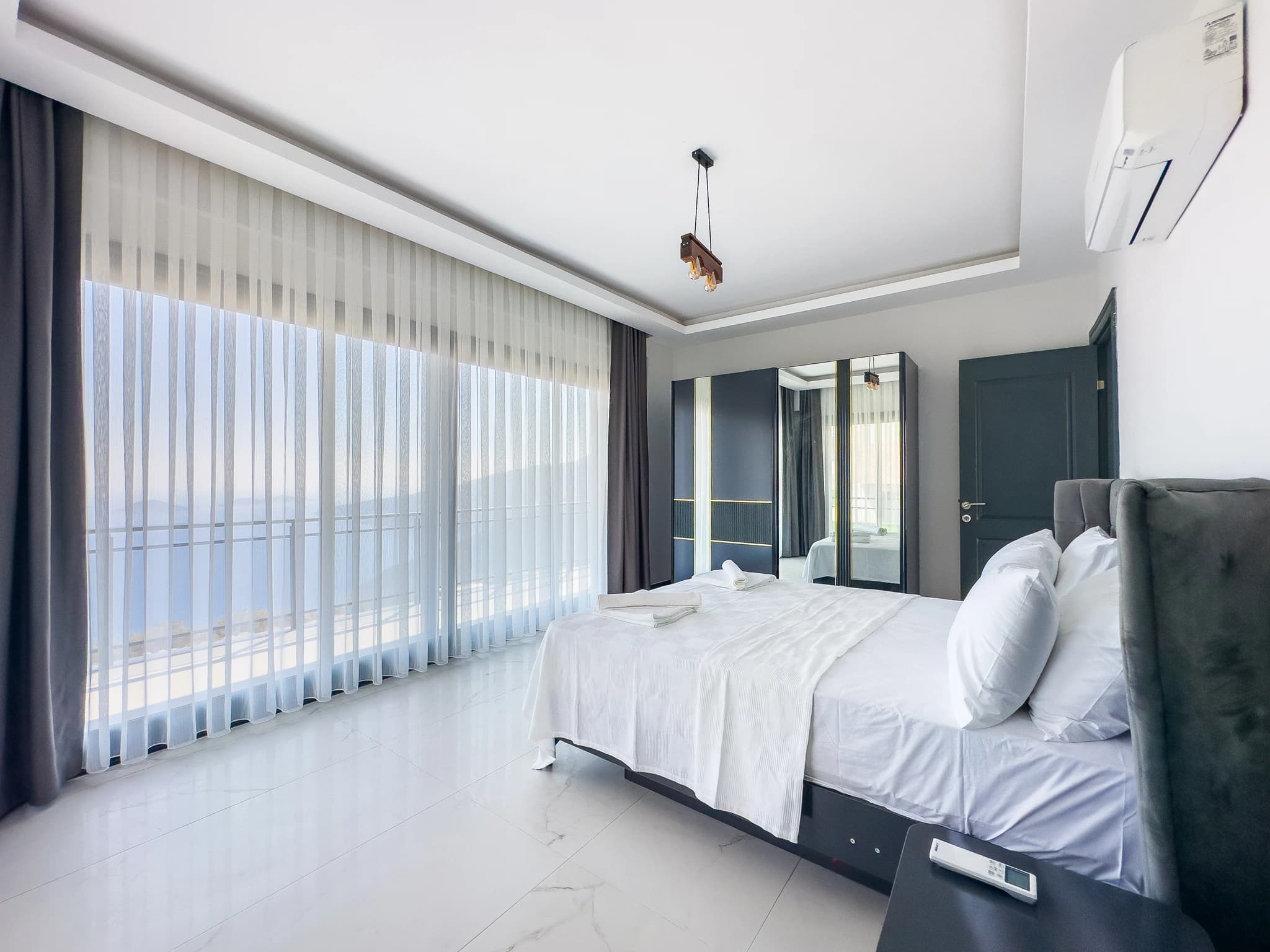 Spacious master bedroom with king bed, floor-to-ceiling windows, and direct balcony access.