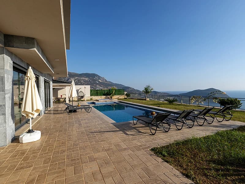 Pool and terrace with sea view, white parasol, and comfortable lounging setup.