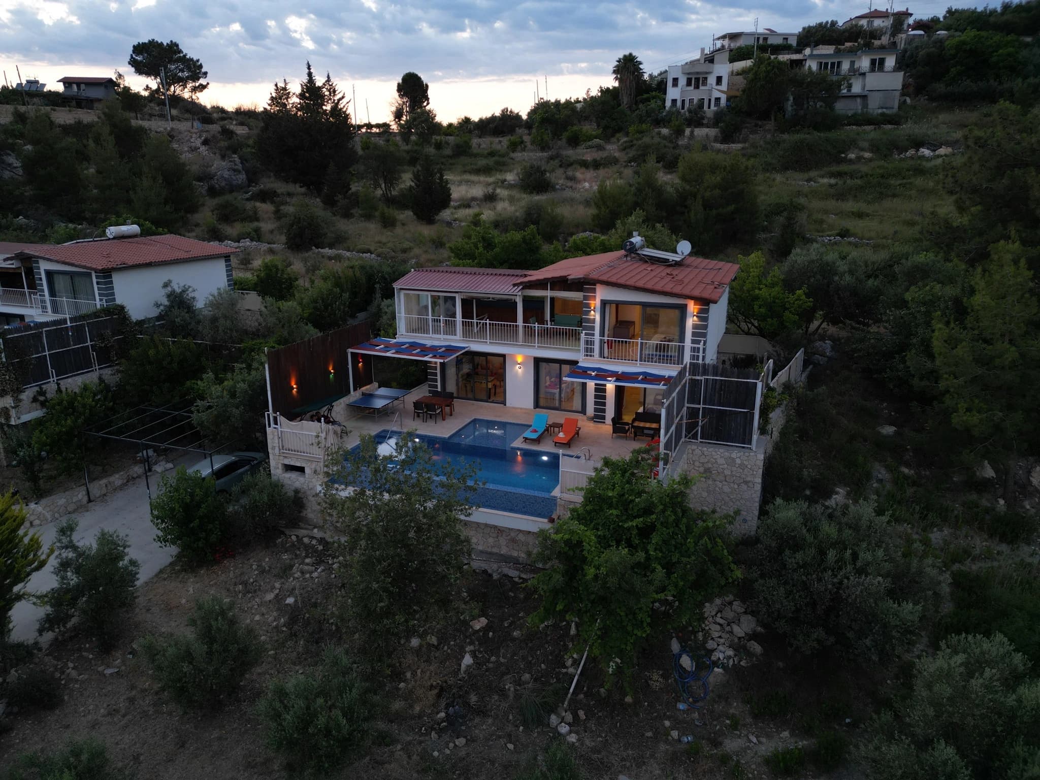 Abgeschiedene Villa mit Natur- und Bergblick, Innen- und Außenpool bei Kalkan – Side view of the villa with pool, landscaped grounds, and countryside setting.
