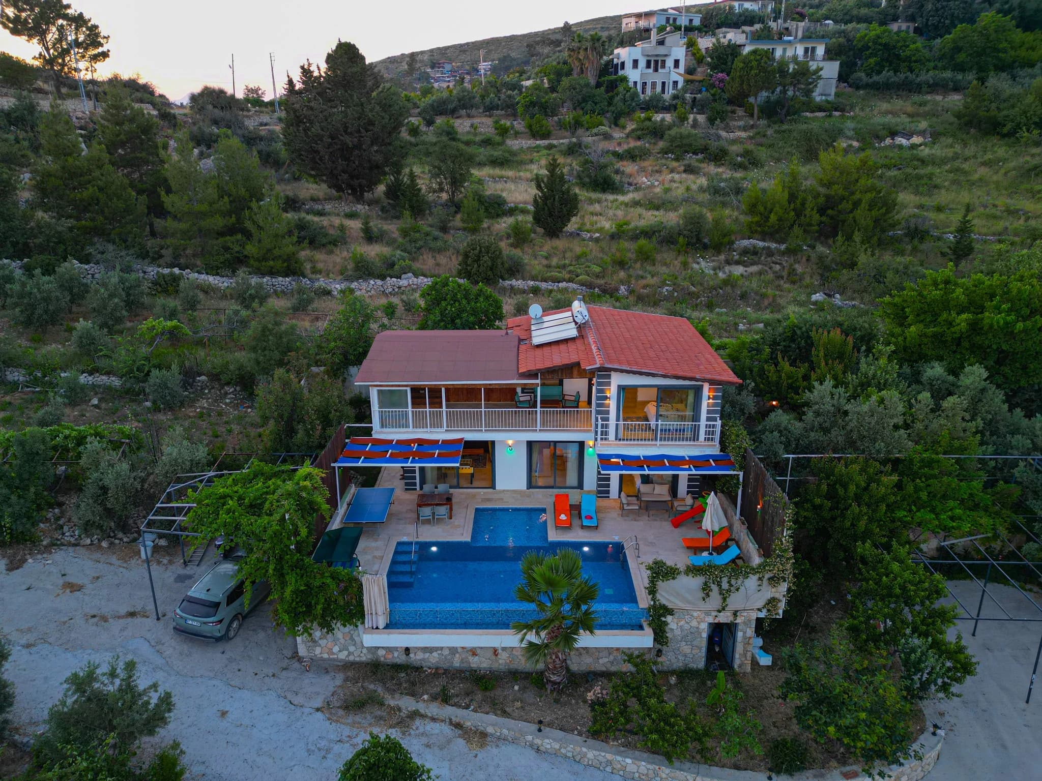 Abgeschiedene Flitterwochen-Villa mit privatem und beheiztem Pool bei Kalkan – Aerial view of the villa's modern exterior with large swimming pool and multiple sun loungers on spacious terrace.
