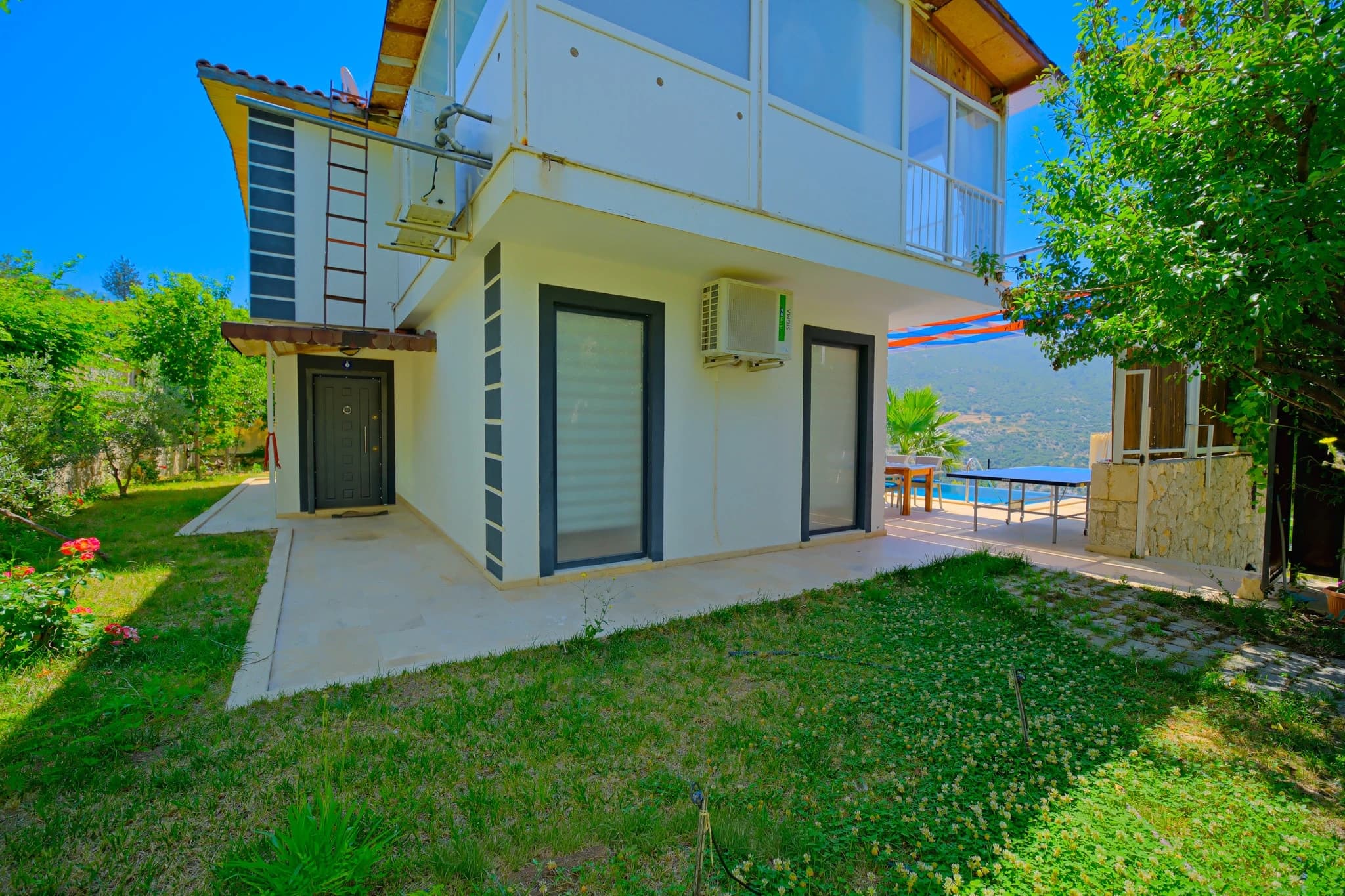 Abgeschiedene Flitterwochen-Villa mit privatem und beheiztem Pool bei Kalkan – Modern white villa exterior with manicured gardens and distant mountain views.