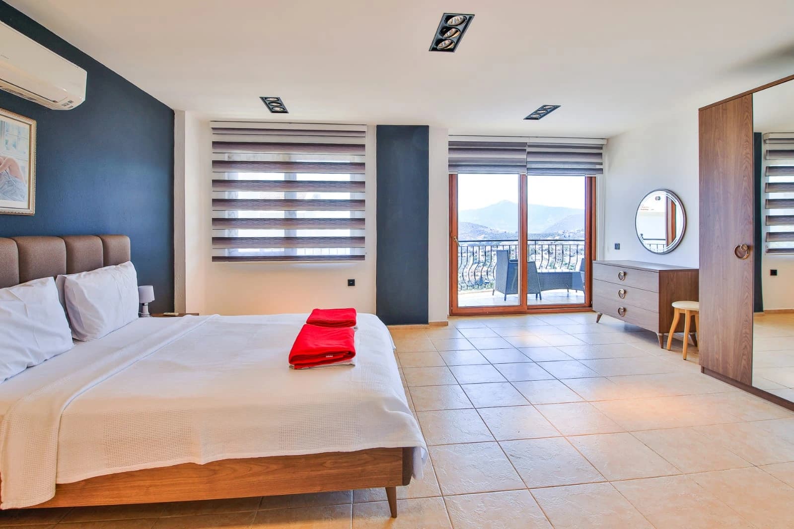 Spacious master bedroom with a double bed, mountain views, and access to balcony with sea view.