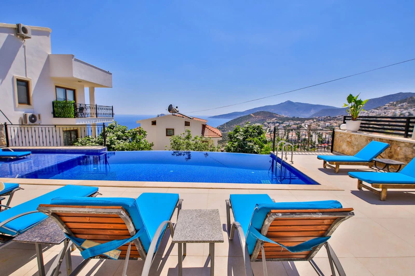 Sparkling private pool with sun loungers overlooking the sea and hillside landscape.