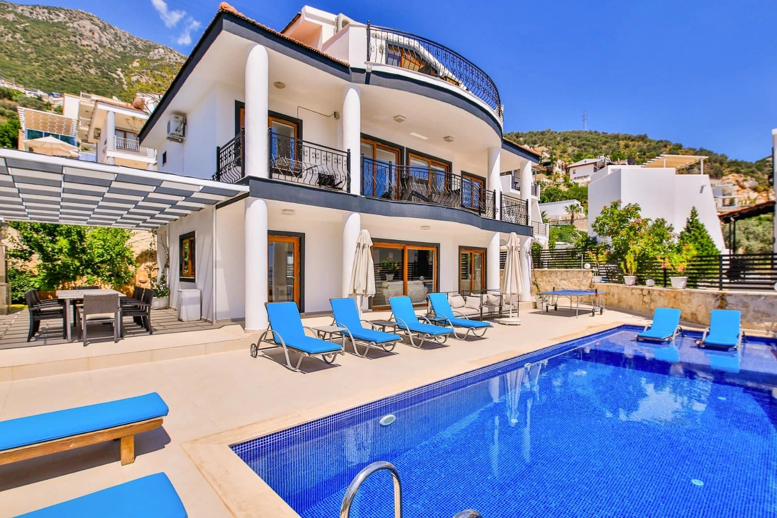Private pool surrounded by sun loungers with hillside mountain views and shaded terrace areas.