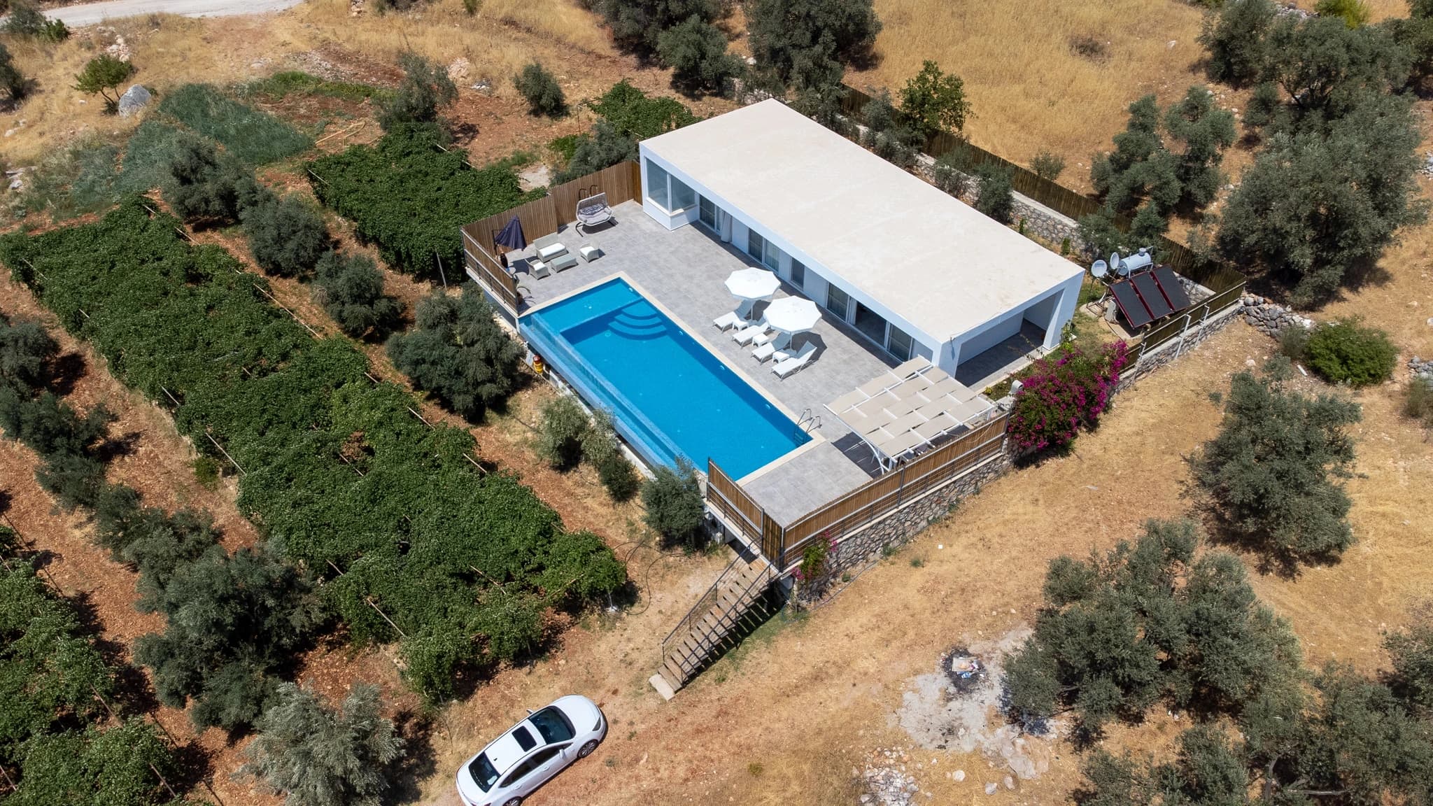Abgeschiedene 2-Zimmer-Villa mit Infinity-Pool und Bergblick bei Kalkan – Aerial view of modern villa with rectangular pool, lounge areas, and surrounding Mediterranean landscape.