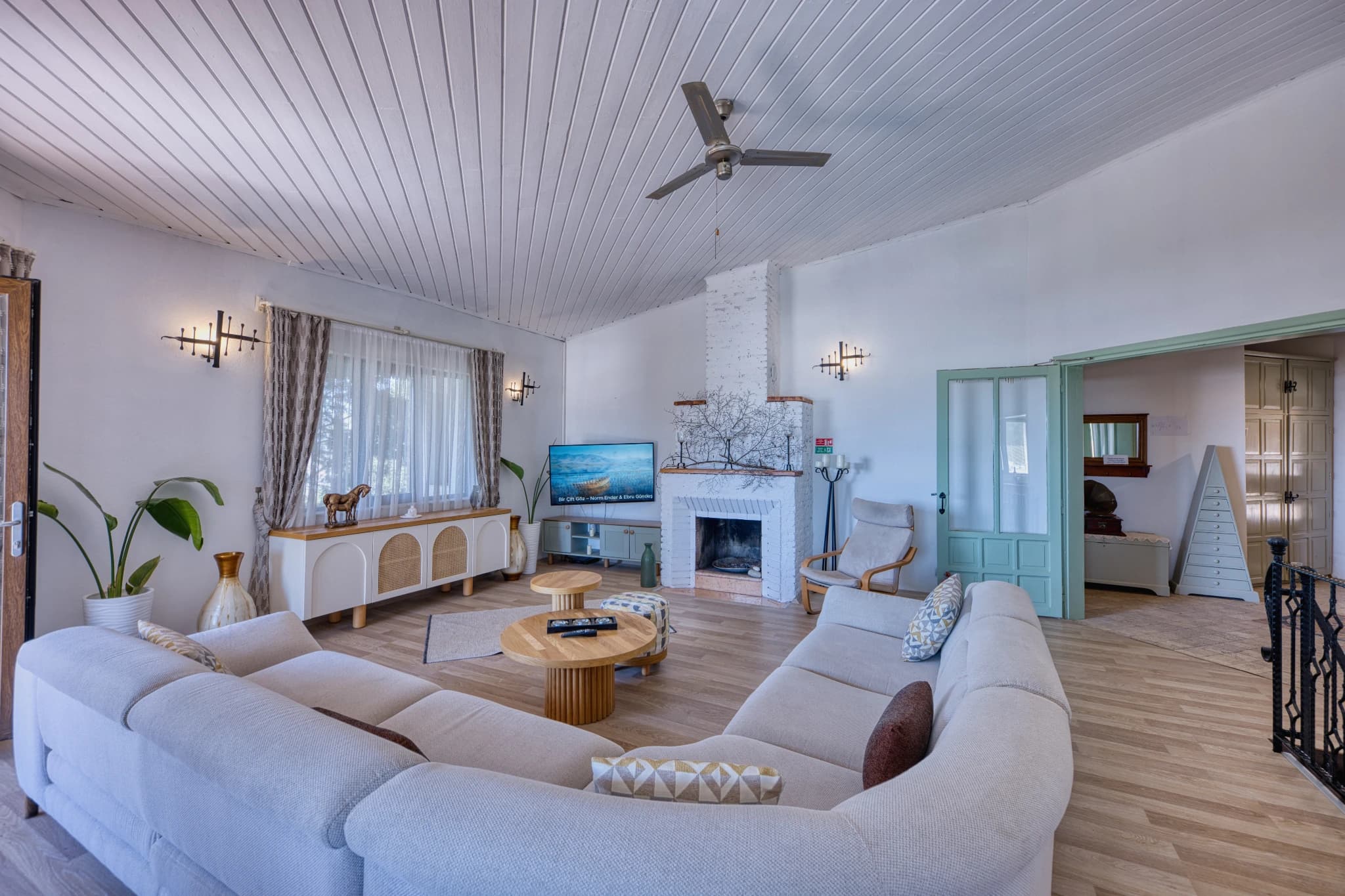 Spacious open-plan living room with curved sofa, fireplace, and modern finishes.