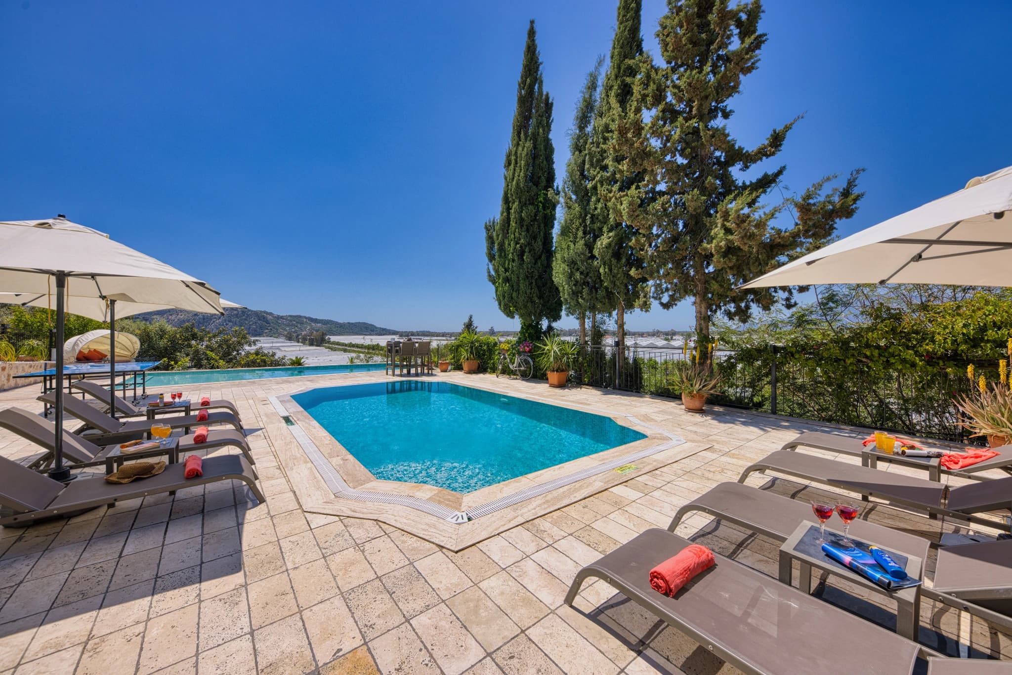 Resort-style pool area with loungers, umbrellas, and mountain backdrop.