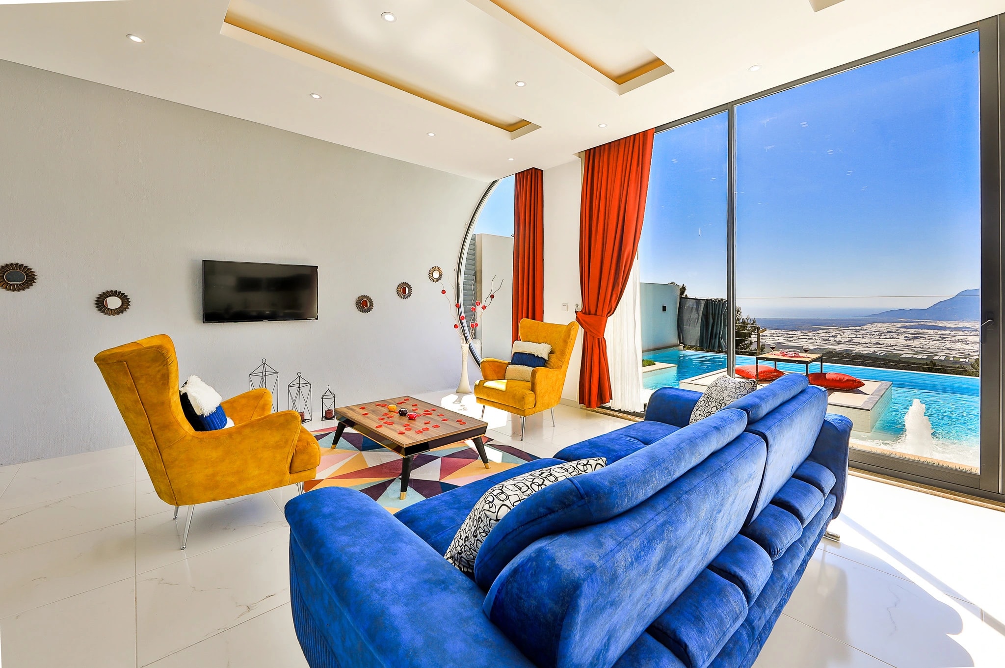 Luxury living room with panoramic sea and mountain views through large windows.