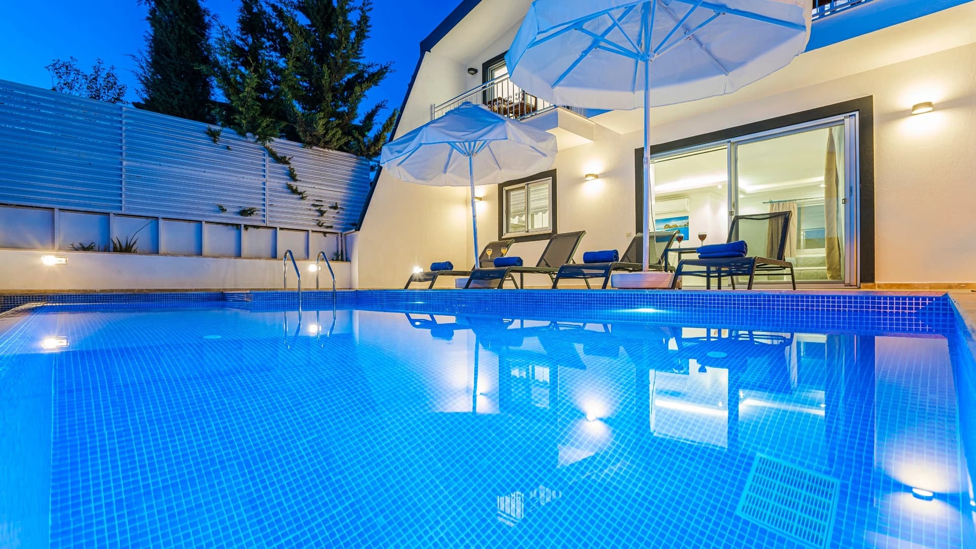 Secluded 2-Bedroom Villa with Heated Pool and Mountain & Sea Views in Kalkan – Crystalline pool at dusk with lounge chairs and pergola shade structure overlooking the property.