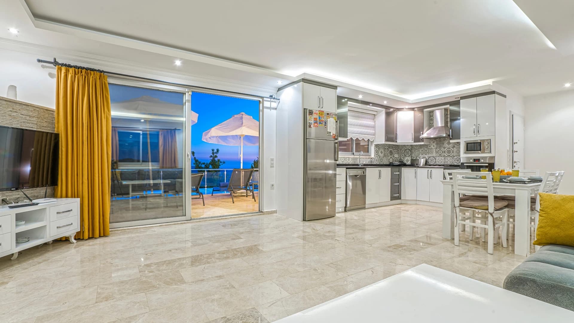 Secluded 2-Bedroom Villa with Heated Pool and Mountain & Sea Views in Kalkan – Modern open-plan living and dining area with kitchen, overlooking pool and sea.