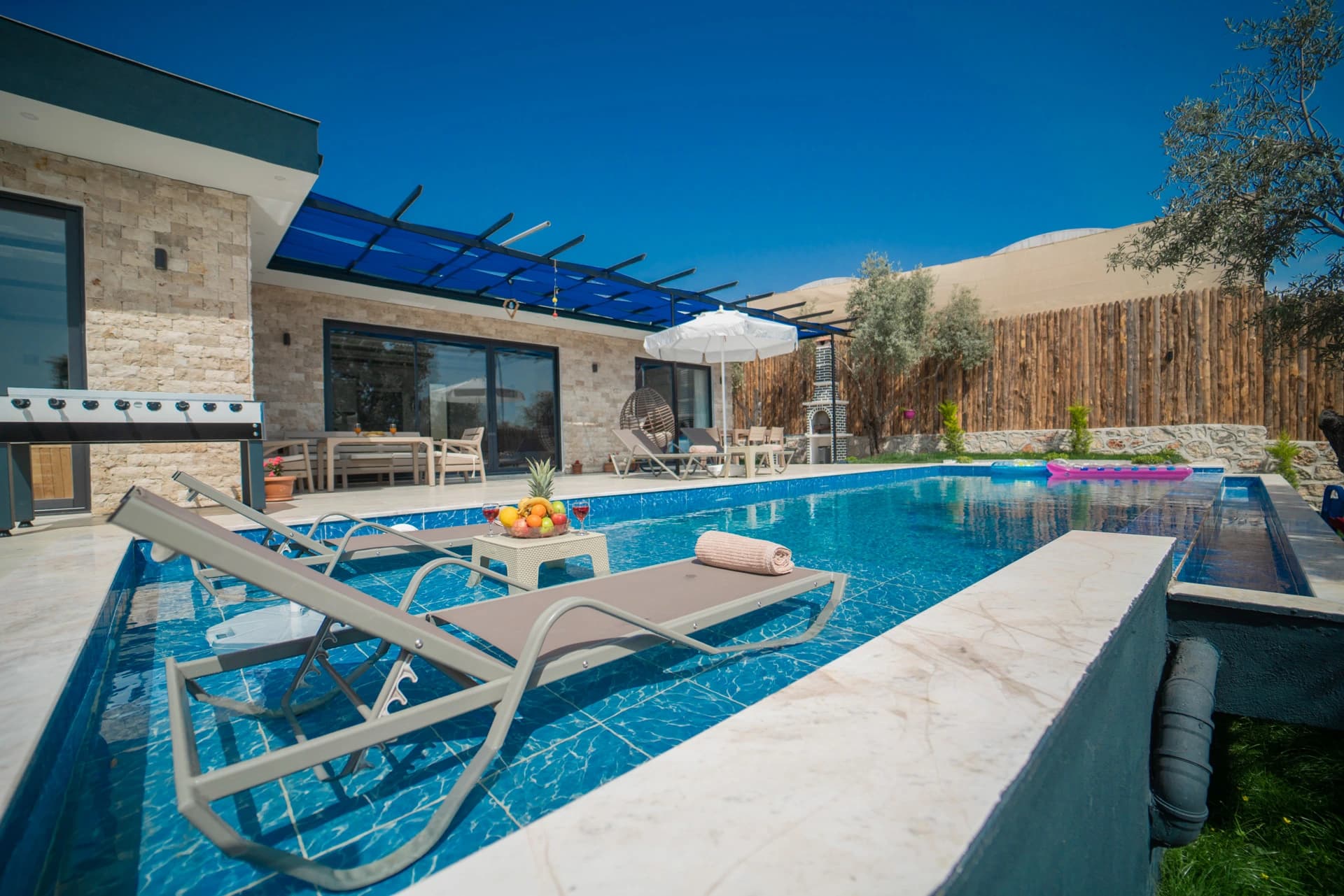 Stunning resort-style pool area with lounge seating, shade structures, and surrounding stone landscape.