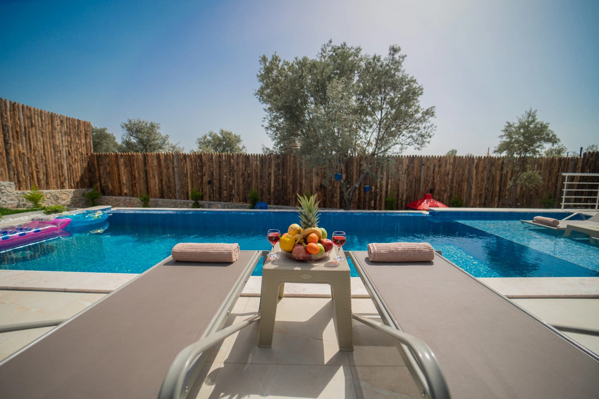 Pristine swimming pool with loungers, fruit display, and refreshments perfectly framed for relaxation.