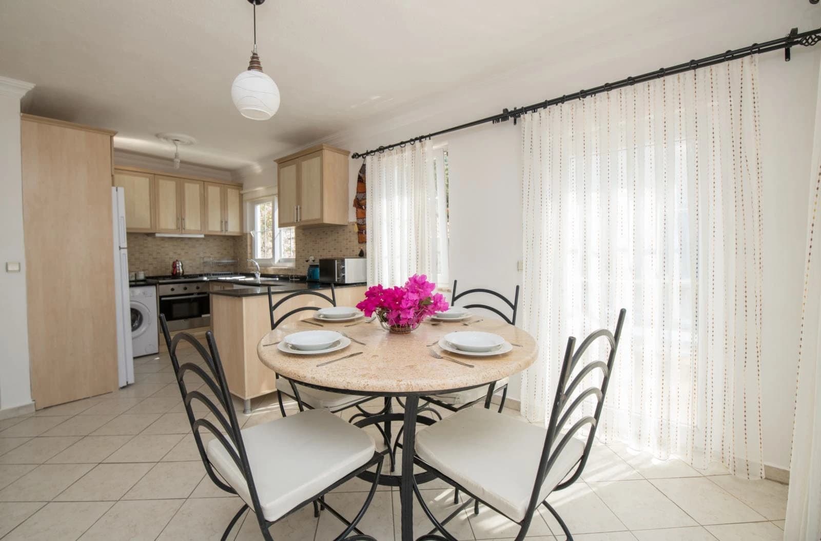 Open-plan dining room and kitchen with round table and direct kitchen access.